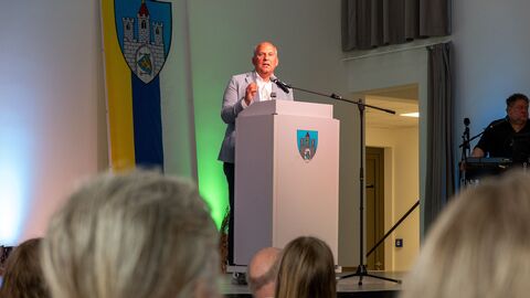 Mann auf Bühne hält Rede zu Publikum.