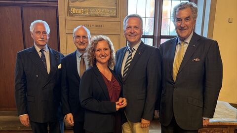 Vier Männer und eine Frau stehen zusammen und lachen in die Kamera.