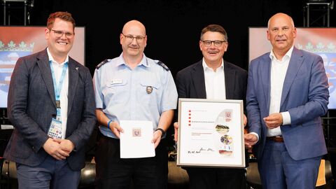 Ministerpräsident Rhein und Innenminister Poseck überreichen eine Urkunde sowie eine Anerkennungsprämie in Höhe von 1.000 Euro an Stadtbrandinspektor Maic Neunert. 