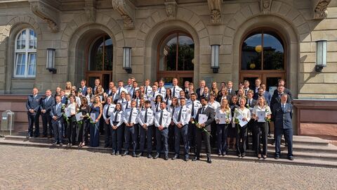 Über 100 Menschen stehen in ihren Polizeiuniformen auf einer Treppe nebeneinander.
