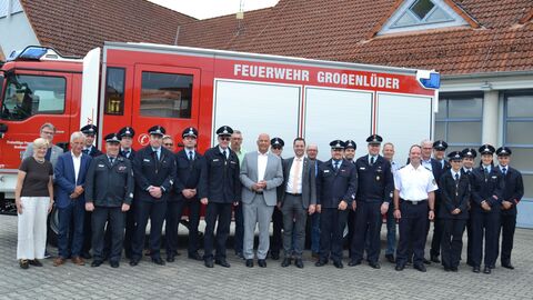 Eine Gruppe steht auf einem Platz vor einem Feuerwehrfahrzeug