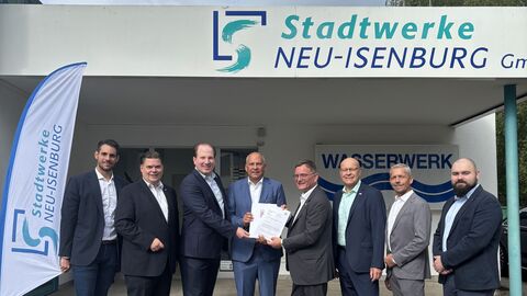 Bescheidübergabe Stadtwerke Neu-Isenburg Mehrere Personen stehen im Anzug vor Stadtwerke Neu-Isenburg.