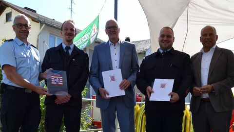 Roman Poseck, Bürgermeister von Beselich und drei uniformierte der freiwilligen Feuerwehr stehen auf einer kleinen Bühne und halten Förderbescheide in den Händen