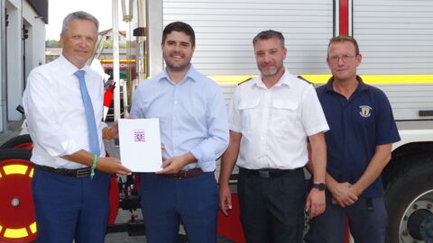 Freiwillige Feuerwehr Reiskirchen  Vier Männer stehen vor Feuerwehrfahrzeug