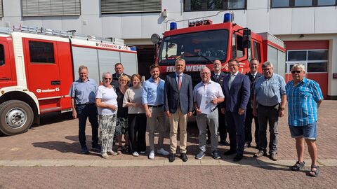 Staatssekretär Martin Rößler übergibt Frank Kummer (Bürgermeister der Gemeinde Wehretal) den Zuwendungsbescheid Staatssekretär Martin Rößler steht mit weitere Personen vor einem Feuerwehrfahrzeug