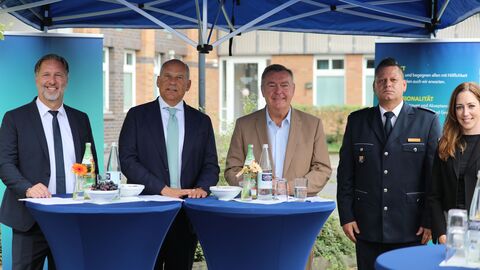 Innenminister Roman Poseck steht mit weiteren Personen bei der Einweihung zusammen an Stehtischen.