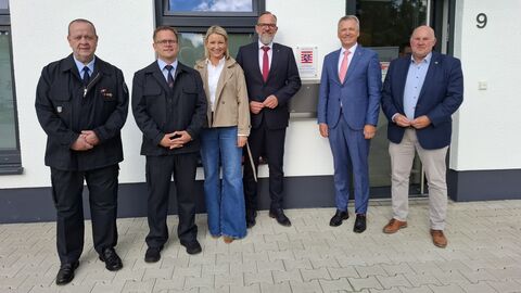 Innenstaatssekretär Martin Rößler steht mit fünf weiteren Personen vor dem Hauseingang des Feuerwehrhauses.