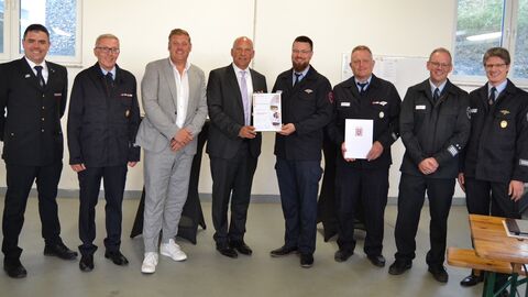 Roman Poseck steht mit sieben Männern in eleganter Feuerwehruniform in einer Reihe.