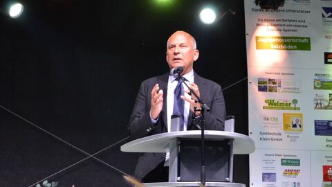 Roman Poseck steht hinter einem Rednerpult und spricht ins Publikum.