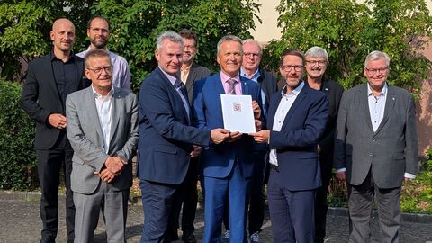 Eine Gruppe Personen steht zur Bescheidübergabe zusammen.