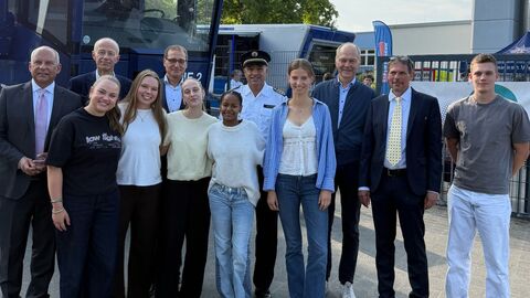 Mehrere Erwachsene sowie Schülerinnen und Schüler stehen vor Polizei-LKW