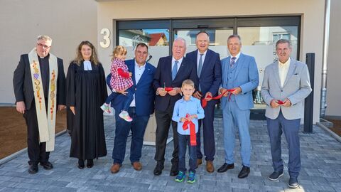 Martin Rößler steht mit einer kleinen Gruppe vor einem Hauseingang - sie halten ein rotes Band und Scheren in den Händen
