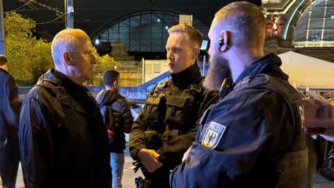 Innenminister im Gespräch mit Polizeibeamten Eine Person unterhält sich mit zwei Polizeibeamten vor dem Frankfurter Bahnhof