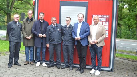 Sieben Männer stehen vor einem Container mit der Aufschrift "Feuerwehr Sprendlingen"