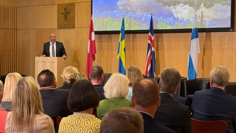 Person hält Rede an Rednerpult vor Publikum