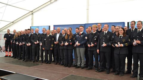 Innenminister Poseck steht mit einer großen Gruppen an Einsatzkräften auf einer Bühne