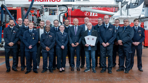 Innenminister Roman Poseck u.a. mit Stadtrat Ludwig Ganzert und Feuerwehrkameraden Eine Gruppe von circa 20 festlich gekleideten Feuerwehrleuten sowie Stadtrat und Minister stehen vor einem Feuerwehrauto