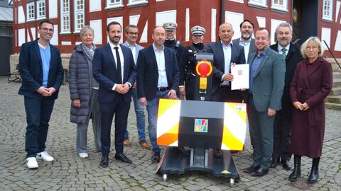 Eine Gruppe steht auf einem Platz in einer Ortschaft bei der Bescheidübergabe.