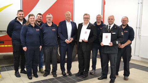 Innenminister Poseck mit Beteiligten der Feuerwehr bei der Bescheidübergabe.