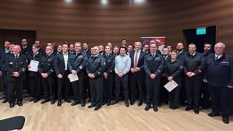 Eine Gruppe von circa 30 Personen meist in festlichen Feuerwehruniformen stehen nebeneinander.