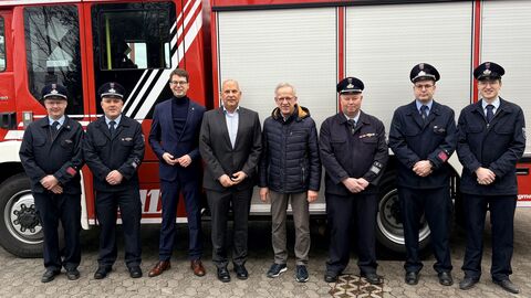 Mehrere Personen stehen vor Feuerwehrauto.