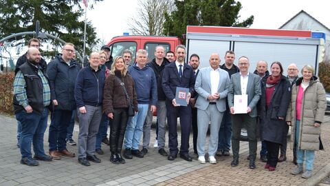 Heimatschutzminister Roman Poseck u. a. mit Vöhls Bürgermeister Karsten Kalhöfer und Angehörigen der Freiwilligen Feuerwehr Basdorf