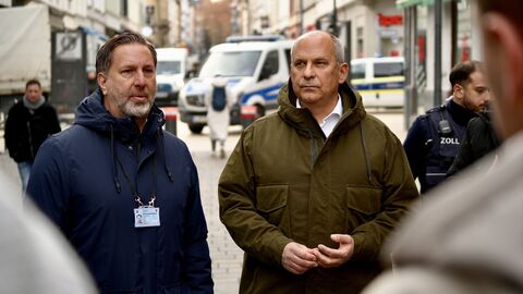 Zwei Männer stehen in Winterjacken auf einer Straße.