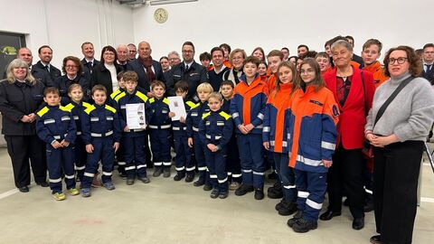 Eine Gruppe von ungefähr 40 Menschen - darunter der Innenminister, weitere Erwachsene aber auch Kinder und Jugendliche in Feuerwehruniformen.
