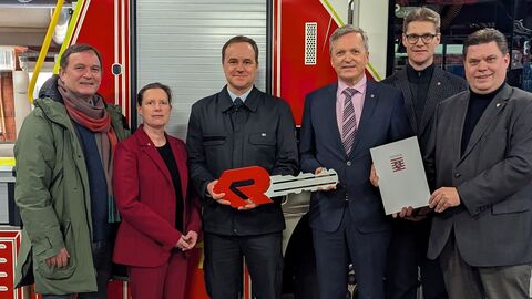 Innenstaatssekretär Martin Rößler steht mit weiteren Personen bei der Bescheidübergabe vor einem Feuerwehrfahrzeug.