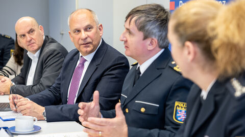 Innenminister Roman Poseck sitzt mit weiteren Personen an einem Tisch