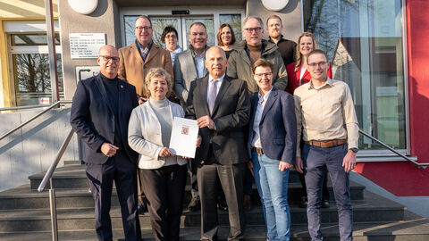 Mehr als zehn Menschen stehen auf einer Treppe vor einem Gebäude.