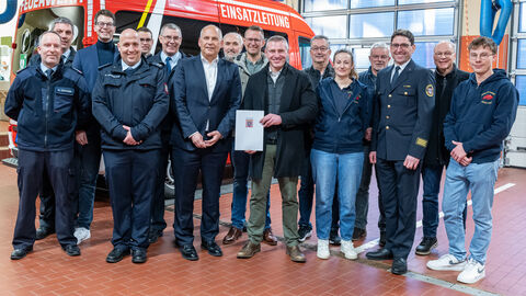 Mehrere Männer stehen vor Feuerwehrauto. 