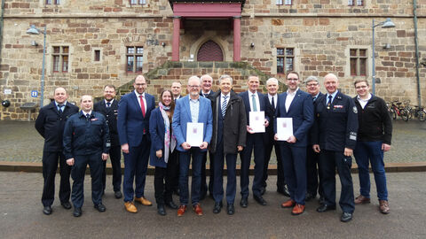 Über zehn Personen stehen draußen vor einem Gebäude aus Stein.