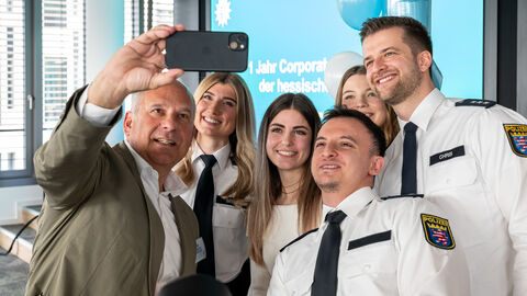 Innenminister Roman Poseck macht ein Selfie gemeinsam mit Polizistinnen und Polizisten