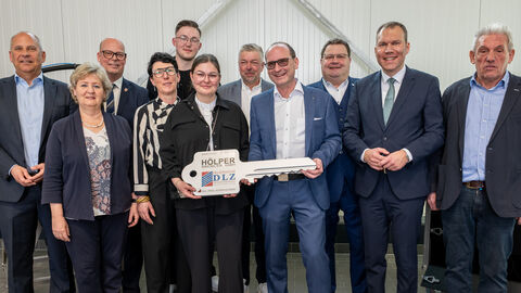 Eine Gruppe von ungefähr 10 Personen stehen zusammen. Zwei halten einen überdimensional großen Schlüssel aus Pappe in den Händen.