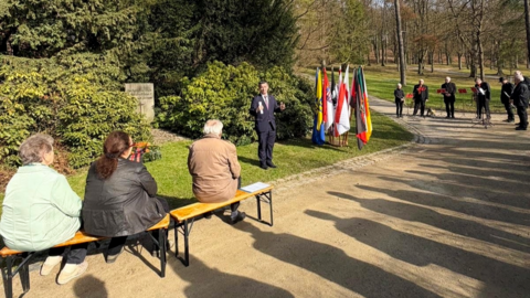Personen sitzen auf einer Bank in einem Park.