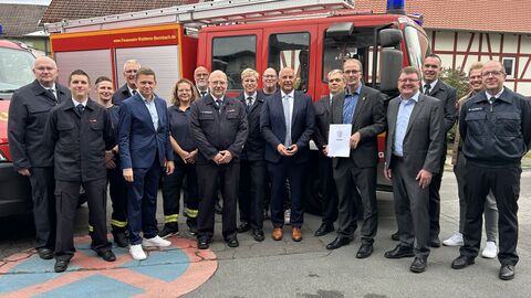 Mehrere Männer und Frauen in Feuerwehr-Uniform stehen nebeneinander vor einem Feuerwehrfahrzeug