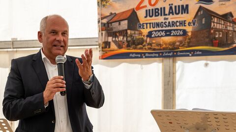Poseck spricht ins Mikrofon - hinter ihm ein Plakat mit der Aufschrift "20 jähriges Jubiläum der Rettungsarche e.V."
