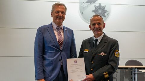 Herr Rößler steht neben einem Mann in Uniform, welcher eine Urkunde in den Händen hält